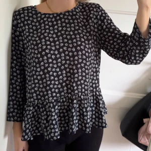 Marinblå blommig blus med volang - Marinblå blus med små vita blommor och volang. Storlek M men passar S också 