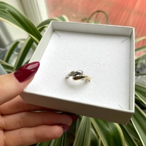 Tvådelad ring i guld och silver - Snygg ring med modern, böljande design i både guld- och silverfärg. Ringen har en twistad form som ger en cool och unik look. Går att ha ringen på olika sätt då den är i två delar! Perfekt för dig som gillar att mixa metaller och vill ha ett statement-smycke på fingret.