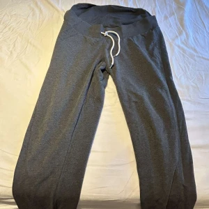 Grå mjukisbyxor med snörning - Mysiga grå mjukisbyxor med bred resår i midjan och vit snörning framtill. Perfekta för chill dagar eller när du vill vara bekväm. Tillverkade i mjukt material som känns skönt mot huden.