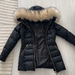 Svart Rockandblue pufferjacka med päls -  Säljer min Rockandblue-jacka i storlek 34. Jackan är i perfekt skick, inga skador, inga fläckar och inga tecken på slitage. Den har snygga guldiga dragkedjor, quiltade detaljer och en stor huva med fluffig päls. Varm och bekväm, passar perfekt nu till hösten/vintern 🌨️✨. Kan mötas upp eller skicka💕.  Pris kan diskuteras💗