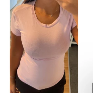 Ljusrosa tight t-shirt - Säljer en ljusrosa t-shirt med tight passform och korta ärmar. T-shirten har en klassisk rund halsringning och är gjord i ett mjukt material som sitter skönt mot kroppen. Perfekt för dig som gillar en enkel och stilren look.