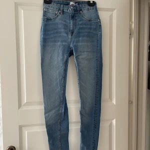 Ljusblå skinny jeans med hög midja - Snygga ljusblå skinny jeans med hög midja och klassisk femficksdesign. Jeansen har en smal passform hela vägen ner och är tillverkade i stretchig denim för extra komfort. Perfekta för dig som gillar en tight och modern look.