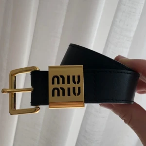 Svart skärp  med gulddetaljer - Snyggt svart bälte med  exklusivt spänne i guldmetall. logga ingraverad och bältet är gjort i slätt skinn. Perfekt accessoar för att lyfta vilken outfit som helst. Tyvärr för kort för mig som är en L/xl