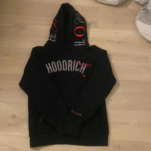 Svart HOODRICH hoodie med tryck - Svart hoodie från HOODRICH med stor logga framtill och text på ryggen. Priset är inte hugget i sten.