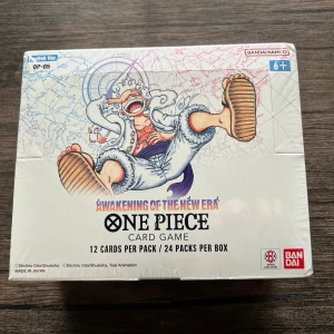 Awakening of the New Era: One Piece Card Game OP-05.(English). - Samlarbox med 24 booster packs från One Piece Card Game! Upptäck 126+1 olika korttyper med episka karaktärer och coola illustrationer. Perfekt för fans av manga, anime och samlarkort. Passar både nya och erfarna spelare. Engelska versionen.