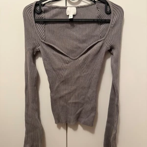 Ribbad grå långärmad topp H&M - Säljer en ribbad grå långärmad topp från H&M i storlek S med  v-ringning och figurnära passform. Ärmarna är även lite långa och rött så stor vid bröst.
