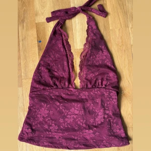 Vinröd spetsig halterneck linnetopp - Aldrig använt🤎Säljer en vinröd halterneck linnetopp med djup v-ringning och knyt i nacken. Toppen har blommigt spetsmönster och är croppad. Perfekt för dig som vill sticka ut med en feminin och trendig look.