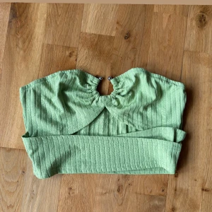 Ljusgrön ribbad bandeau topp - Säljer en ljusgrön bandeau topp med ribbad struktur och snygg detalj med ringning framtill. Toppen är axelbandslös och har en fräsch, somrig vibe. Perfekt att styla med höga jeans eller kjol💚