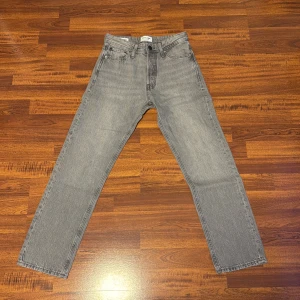 Gråa Jack & Jones Jeans - Tja! Säljer ett par snygga Jack & Jones Jeans i färgen ljusgrå. Det är modellen Chris och dom sitter som loose/regulare fit. Passar till både vardag och fest. Skick: 9/10 använd ett fåtal gånger fortfarande fint skick inga defekter. Storlek: W27 L30. Pris 250kr pris kan diskuteras vid snabb affär💨Kom DM vid fler bilder eller funderingar🥰