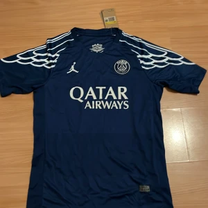 PSG x Jordan blå fotbollströja S - Snygg blå Paris Saint-Germain fotbollströja från Jordan med vita detaljer och vingar på axlarna. Tröjan har korta ärmar, broderad PSG-logga och Qatar Airways-tryck på bröstet. Tillverkad i lätt Dri-FIT-material som andas. Perfekt för dig som älskar fotboll och streetstyle. Pris kan diskuteras vid snabb och smidig affär😊😊