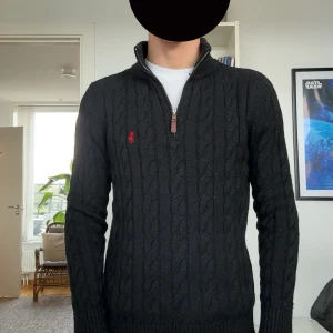 Ralph Lauren halfzip - Svart kabelstickad tröja från Ralph Lauren i väldigt bra skick. Kostar över 2000 kr ny. Storleken har krympt lite och den passar nu för S.