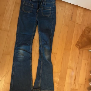 Blå jeans från your denim your rules👖 - Snygga blå jeans från Your Denim Your Rules i klassisk bootcut-modell. Jeansen har fem fickor, kontrastsömmar och dragkedja framtill. Tillverkade i jeansmaterial med coola slitningar på benen för en avslappnad look.