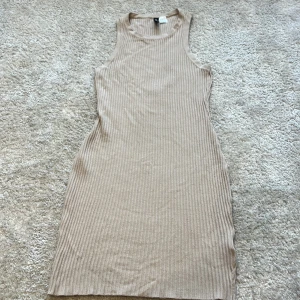 Beige ribbad klänning från H&M Divided - Säljer en beige ribbad kortklänning från H&M Divided i storlek S. Klänningen är ärmlös med rund halsringning och har en slim passform som framhäver figuren. Perfekt för dig som gillar en enkel och stilren look. Kontakta för fler bilder 🩷