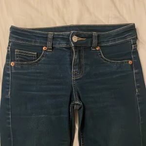 Mörkblå bootcut jeans skit snygga och väldigt bootcut  - Snygga mörkblå jeans med bootcut passform och klassiska fem fickor. Jeansen har kontrastsömmar och lätt slitning framtill och baktill för en cool look. Tillverkade i stretchigt denim som sitter skönt hela dagen.