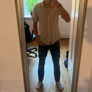 Beige linneskjorta från C! i S - Säljer en stilren beige skjorta från C! i regular fit. Skjortan är kortärmad och tillverkad i en skön blandning av linne och bomull. Perfekt för varma dagar med sin luftiga känsla och klassiska knappstängning framtill.