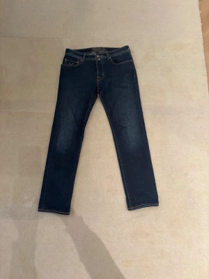 Jacob Cohen Jeans  - Jacob cohen jeans i färgen medium blue ungefär med de klassiska lite gula sömmarna. Den har den klassiska hästen bak på jeansen såklart också. De är handgjorda och så kallade tailored jeans. I en region som kallas Veneto i Italien är de gjorda. Modell: 688 Comfort. De sitter som lite mer pösig slim fit så någon stans emellan slim och regular. Pris: 1699kr! Kan gå ner i pris vid snabb affär. Skickar samma dag som paketet köpts! Mvh Sverigesresell