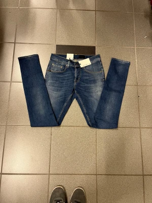 Tiger of Sweden jeans blå W29 L34 - Snygga blå jeans från Tiger of Sweden med smal passform och smal fot. Klassisk femficksdesign, gul kontrastsöm och läderpatch med T/J-logga bak. Perfekt för dig som gillar stilrena och tajta jeans.