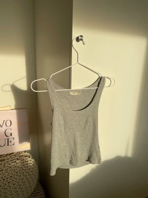 Grå ribbad linnetopp från Pull&Bear - Säljer en grå ribbad linnetopp från Pull&Bear i storlek XS. Toppen är ärmlös med rundad halsringning, använd några gånger och har en liten kaffe fläck som inte gick bort när jag tvättade den. 💞