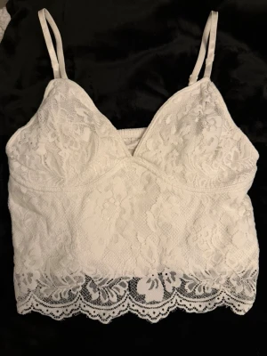 Spetstopp - Säljer denna ursnygga spetstopp med smala axelband och v-ringad front. Baksidan har elastisk rynkning för extra komfort. Perfekt till fest! 🎉Toppen är som ny och har inga defekter💕Hör av dig vid minsta fundering!✨