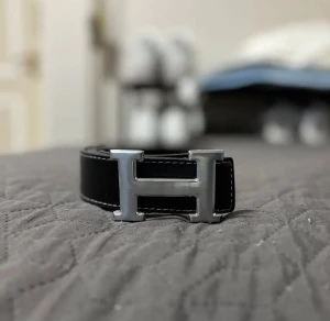 H bälte  - Snyggt svart skärp med ett H-format metallspänne i silverfärg. Perfekt accessoar för att lyfta din outfit med en stilren detalj.