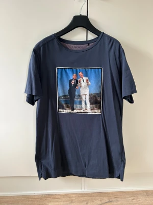Mörkblå t-shirt från Limitato med print - Snygg mörkblå t-shirt från Limitato med ett stort färgglatt print på bröstet från filmen ”Dirty Rotten Scoundrels”