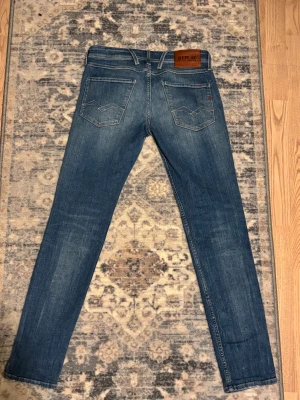 Replay Anbass blå jeans med slitningar - Säljer ett par Replay Anbass jeans i blå tvätt med coola slitningar och detaljer på benen. Köpta för ett år sedan men knappast använda. Nytt skick. Pris kan diskuteras vid snabb affär.