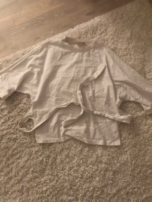 Vit omlottopp med knyt från Nelly - Säljer en vit omlottopp från Nelly i storlek XS. Toppen har breda, korta ärmar och ett snyggt knytband i midjan som ger en cool och avslappnad look. Materialet är mjukt och känns som bomull, perfekt för vår och sommar. Den är lite skrynklig men går att stryka såklart 💞