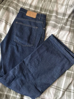Mörkblå raka jeans - Snygga mörkblå jeans med klassisk femficksdesign och raka ben. Jeansen har kontrastsömmar och ett brunt patch vid linningen bak. Perfekta för dig som gillar enkel och tidlös stil. Materialet är slitstarkt jeans och passformen är normal.