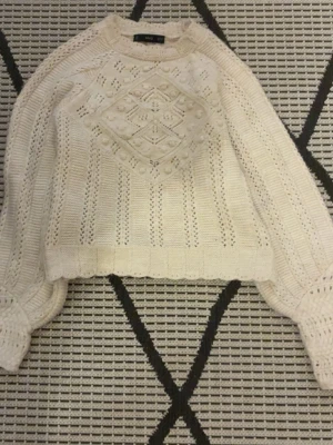 Stickad beige tröja från MNG - Stickad beige tröja från MNG med snyggt mönster och struktur på bröstet. Tröjan har långärmade ballongärmar och är croppad i modellen. Perfekt för dig som gillar detaljer och vill ha en mysig men trendig look.