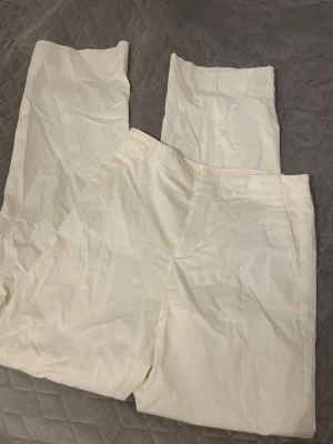 Nya kostymbyxor från Pull&Bear - Dom har nån liten fläck där bak men går bort i tvätten. Snygga vita kostymbyxor från Pull&Bear i storlek XS. Byxorna har raka ben, hög midja och diskreta fickor bak. Materialet är bomull och de har en clean look som passar till många stilar. Perfekta för dig som gillar minimalistiskt och fräscht.
