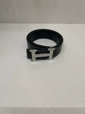 Svart Bälte med H-spänne - Bältet har inga defekter och är i storlek 110 cm