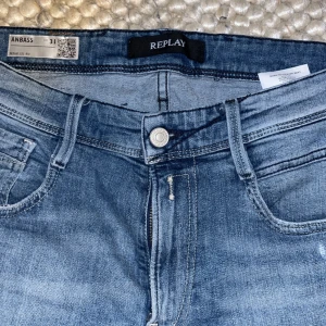 Replay Anbass  - Säljer ett par Replay Anbass jeans i blå tvätt med snygga slitningar och klassisk femficksdesign. Dom är tillverkade i stretchigt denim för extra komfort. Perfekta för dig som gillar en modern och avslappnad stil. Pris kan diskuteras!