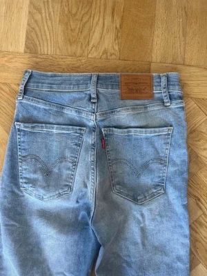 Levi's Mile High Super Skinny jeans - Säljer ett par ljusblå Levi's Mile High Super Skinny jeans med hög midja. Modellen har klassiska fem fickor, Levi's läderpatch bak och smal passform hela vägen ner. Jeansen är gjorda i mjuk bomull med stretch för extra komfort.