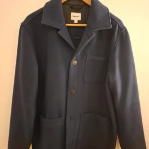 Mörkblå overshirt  - Snygg mörkblå overshirt från Kappahl med klassisk krage och tre praktiska fickor framtill. Jackan har knäppning med två knappar och är långärmad. Perfekt för lager-på-lager och en clean look.