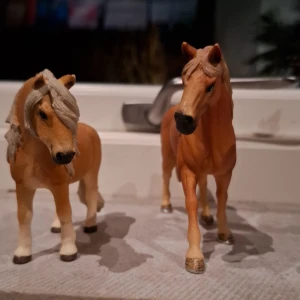Ej elektronikprodukt - Bilderna visar två realistiska hästfigurer i plast, troligen leksaker eller samlarobjekt. De är ljusbruna med detaljerad man och svans. Inga synliga defekter eller slitage. Ej elektronik.