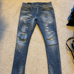 Blå slitna skinny jeans från Dondup - Säljer ett par blå skinny jeans från Dondup, modell George. Jeansen har slitningar, färgstänk. Storlek 31, bra skick. Kommer med tag