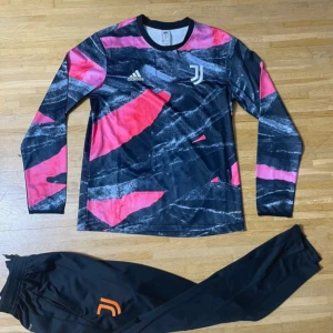 Juventus långärmad fotbollströja Adidas - Juventus långärmad fotbollströja från Adidas med coolt abstrakt mönster i svart, rosa och grått. Tröjan har klubbens logga på bröstet och är tillverkad i lätt, ventilerande polyester. Perfekt för träning eller match!