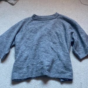 Grå stickad tröja från 157 XS - Mysig grå stickad tröja från 157 i storlek XS. Tröjan har rund hals med ribbad kant och trekvartsärmar. Perfekt för dig som gillar enkel och chill stil med en neutral färg. Passar dig som vill ha en basic och skön tröja till hösten eller vintern.