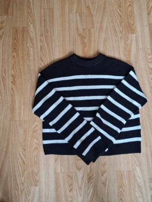 Svartvit randig stickad tröja H&M - Randig stickad tröja från H&M i svart och vitt. Tröjan har en rund halsringning och långa ärmar. Den är ribbad i materialet och har en loose passform som ger en chill vibe. Perfekt för dig som gillar klassiska stripes och vill ha en enkel men snygg look.