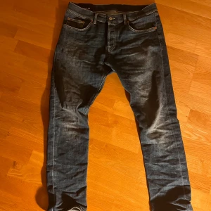 Mörkblå jeans från dondup - Snygga mörkblå jeans från dondup Jeans med klassisk femficksdesign och orangea detaljer på bakfickan. Jeansen har en slim passform och är tillverkade i slitstarkt denim med coola slitningar framtill. Perfekta för dig som gillar streetstyle.