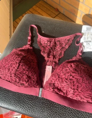 Vinröd spets bralette XL - Säljer en vinröd bralette från Swegmark i storlek XL. Toppen är i mjuk spets med fina detaljer och har smala axelband samt bred resår under bysten. Perfekt för dig som gillar en feminin och bekväm stil.