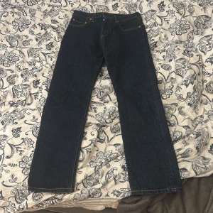 Levi's 501 Premium jeans mörkblå - Säljer ett par klassiska Levi's 501 Premium jeans i mörkblå tvätt. Modellen har rak passform, fem fickor och snygga kontrastsömmar. Jeansen är tillverkade i robust bomullsdenim och har den ikoniska läderpatchen bak.
