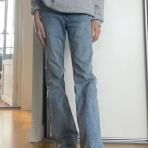 Ljusblå bootcut jeans från H&M Divided - Säljer ett par ljusblå bootcut/vida jeans från H&M Divided i storlek 34. Jeansen har klassisk femficksmodell, normal passform. Snyggt slitna detaljer nertill på benen för en avslappnad vibe. Små defekter som syns på de sista bilderna 