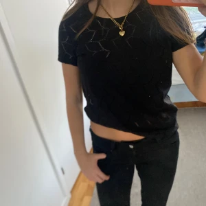 Svart stickad topp från Jacqueline de Yong - Säljer en svart stickad topp från Jacqueline de Yong i storlek S. Toppen har korta ärmar och ett snyggt hålmönster som ger en cool vibe. Modellen är croppad och passar perfekt till höga jeans. Superenkel att styla med smycken och accessoarer.