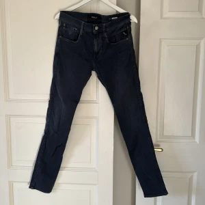 Replay Anbass jeans mörkblå herr - Snygga mörkblå Replay Anbass jeans med klassisk femficksdesign och raka ben. Jeansen har diskreta sömmar, Replay-logga på fickan och patch bak i midjan. Tillverkade i mjukt bomullsmaterial med en slim passform som sitter riktigt schysst.