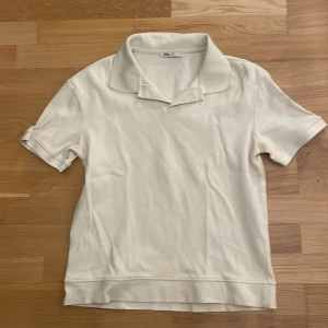 Beige Zara pikétröja - Snygg beige pikétröja från Zara med klassisk krage och korta ärmar. Perfekt för en clean och stilren look.