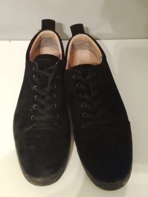 Svarta sneakers med röd sula - Stilrena svarta sneakers med snörning och rund tå. Ovandelen är i mocka och sulan är svart med en cool röd undersida. Perfekta för dig som vill ha en enkel men ändå unik look.