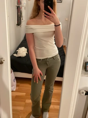 Vit offshoulder topp - Snygg vit offshoulder topp med bred krage som vilar över axlarna. Toppens passform är tight och den är ärmlös, vilket ger en stilren och modern look. Perfekt att matcha med jeans eller kjol för en trendig outfit.