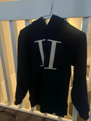 Marinblå hoodie Les Deux med stor logga - Snygg marinblå hoodie från Les Deux med stor vit broderad logga på bröstet. Klassisk huva och mjukt material.