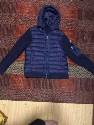 Mörkblå dunjacka med huva från Moncler - Snygg mörkblå cardigan från Moncler med quiltad front och huva. Jackan har ribbade ärmar och sidor i stickad kvalitet samt dragkedja framtill. Klassisk Moncler-logga på ärmen och två fickor med knappstängning. Vissa vad du har att erbjuda så kanske vi kan diskutera fram ett pris stolen M skulle passa som S prislappen är inte på fast finns och den skickas med 